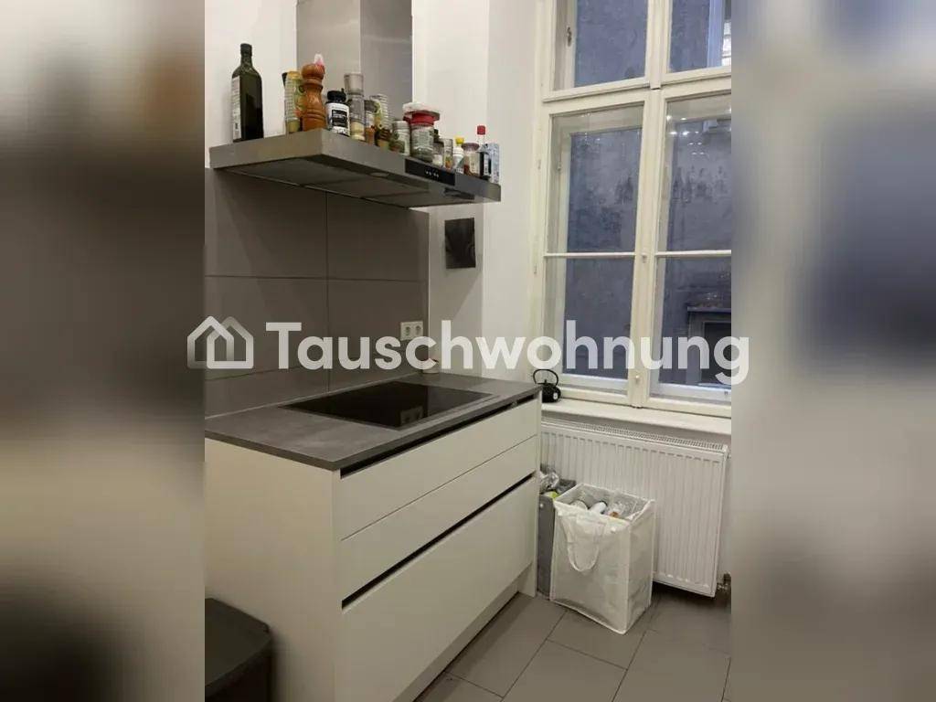 Moderne Küche mit Induktionskochfeld, Dunstabzugshaube und weißen Schränken, daneben ein Fenster.
