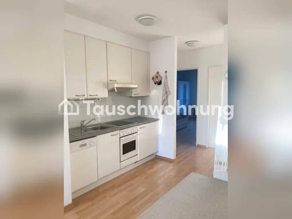 Funktionale Küche mit weißen Schränken, integrierten Geräten und hellem Holzfußboden.