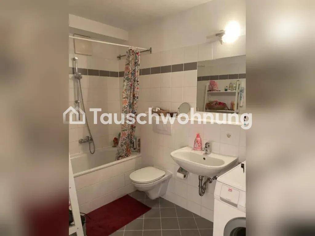 Helles Badezimmer mit Badewanne, Dusche, WC und Waschbecken, gefliest in Weiß und Grau.