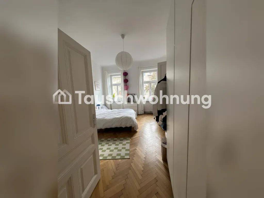 Schlafzimmer mit Holzboden, weißem Kleiderschrank und Blick auf die Fenster, die viel Licht hereinlassen.