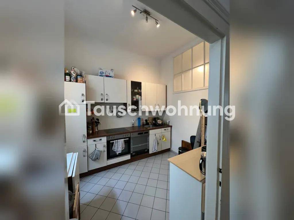 Funktionale Küche mit weißen Schränken, Fliesenboden und einem Fenster für Tageslicht und Belüftung.
