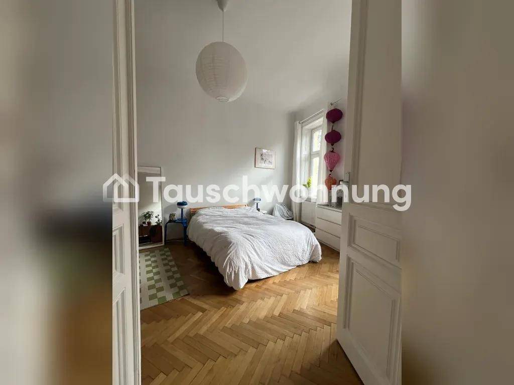 Gemütliches Schlafzimmer mit Doppelbett, Fischgrätparkett und viel Tageslicht durch große Fenster.