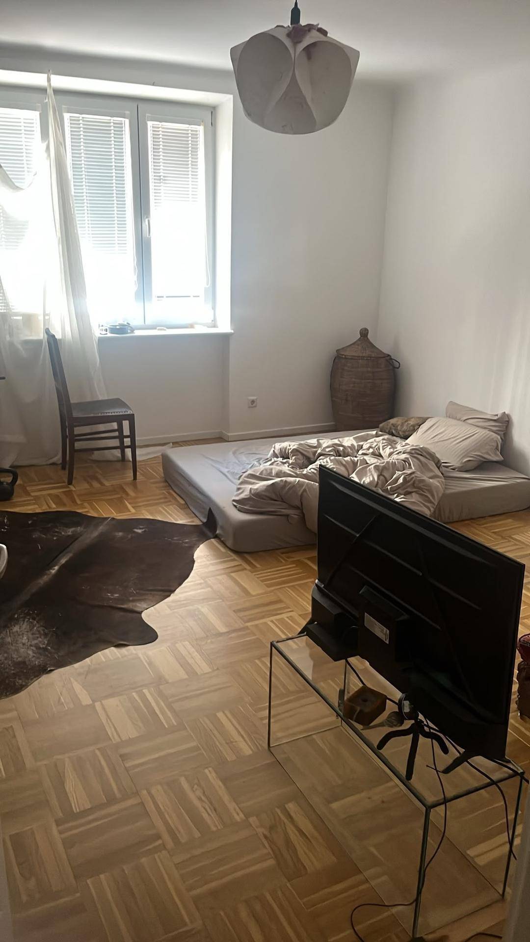 Geräumiges Schlafzimmer mit Parkettboden, einem Bett auf dem Boden und viel Tageslicht.