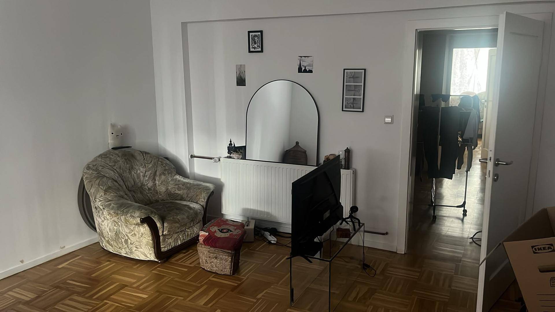 Gemütliches Wohnzimmer mit Parkettboden, einem Sessel und einem großen Spiegel an der Wand.