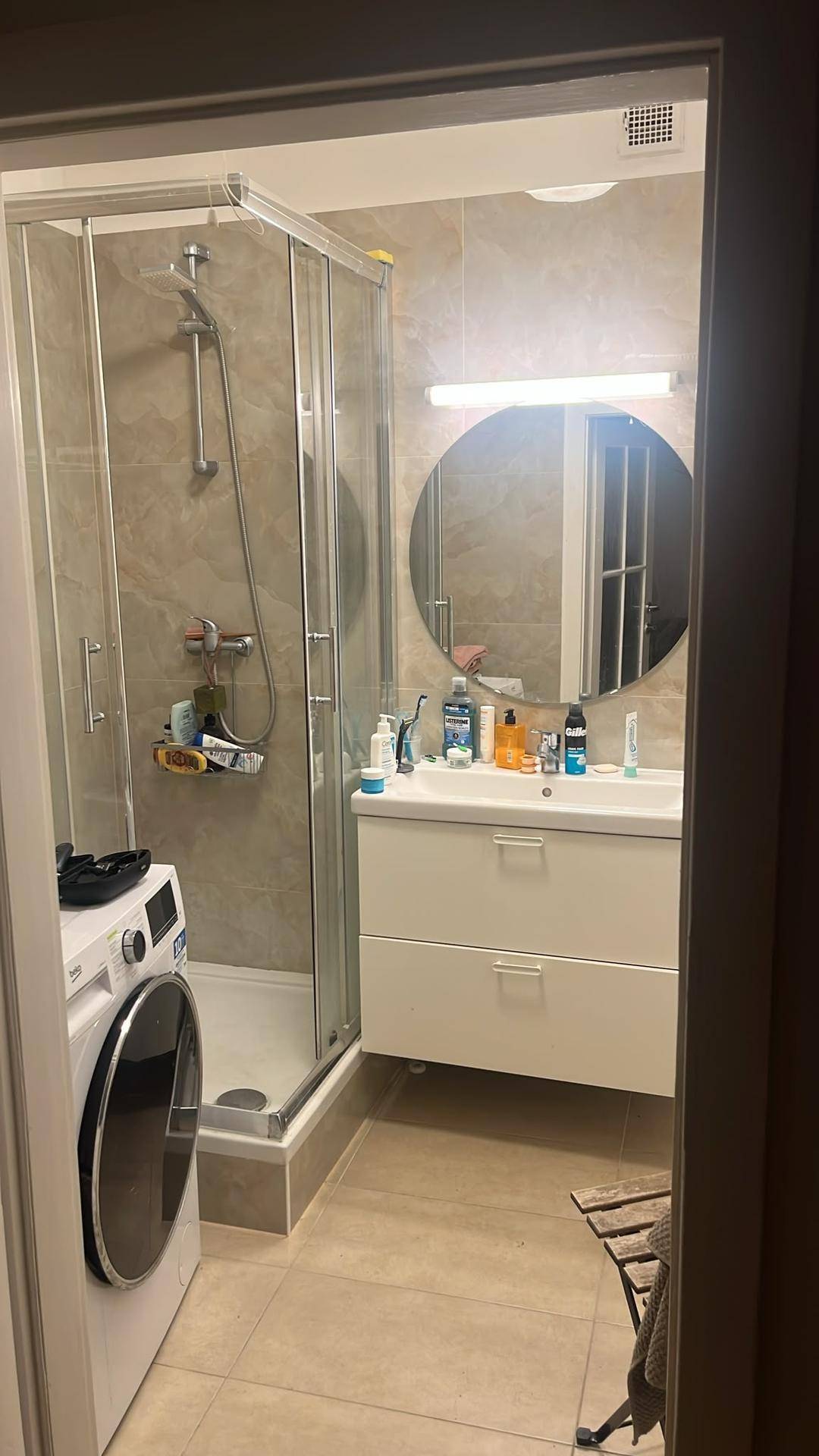 Modernes Badezimmer mit Duschkabine, Waschbeckenunterschrank und integrierter Waschmaschine.
