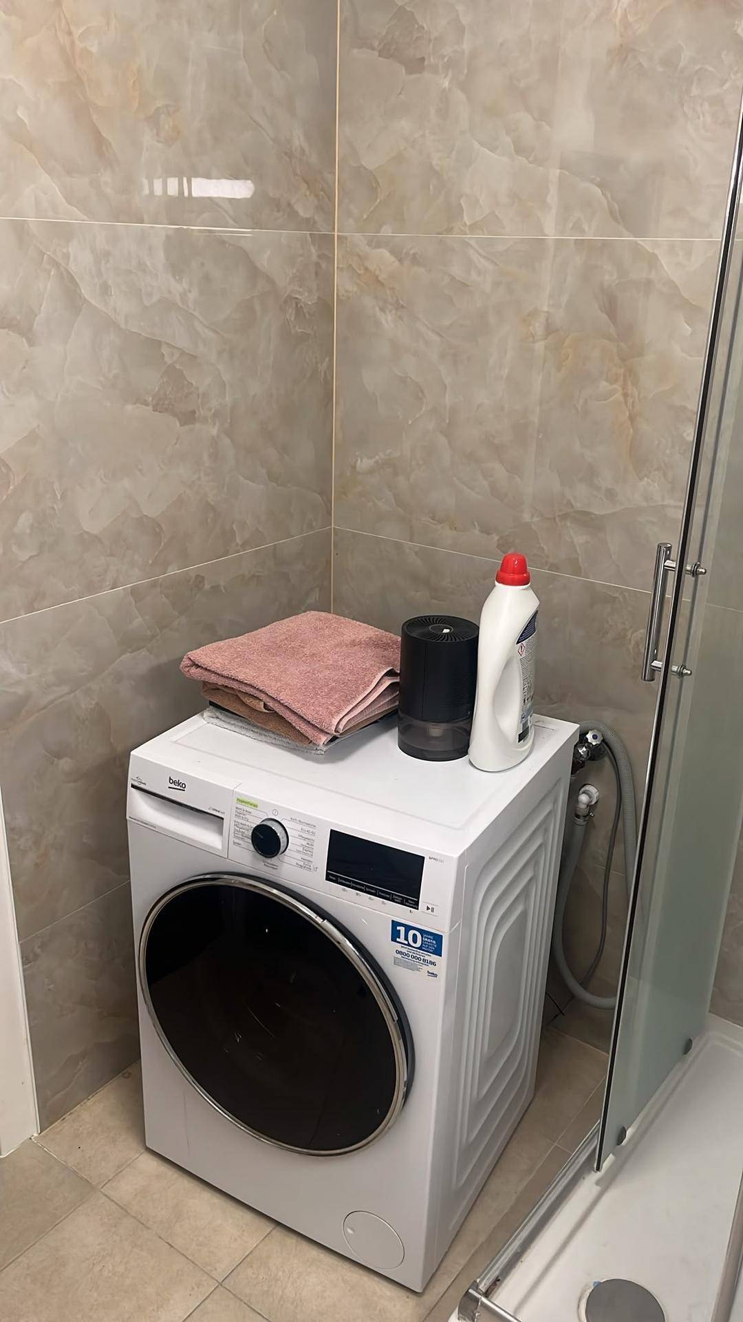 Waschmaschine in einem gefliesten Bereich, ideal für Wäsche und Haushaltsaufgaben.