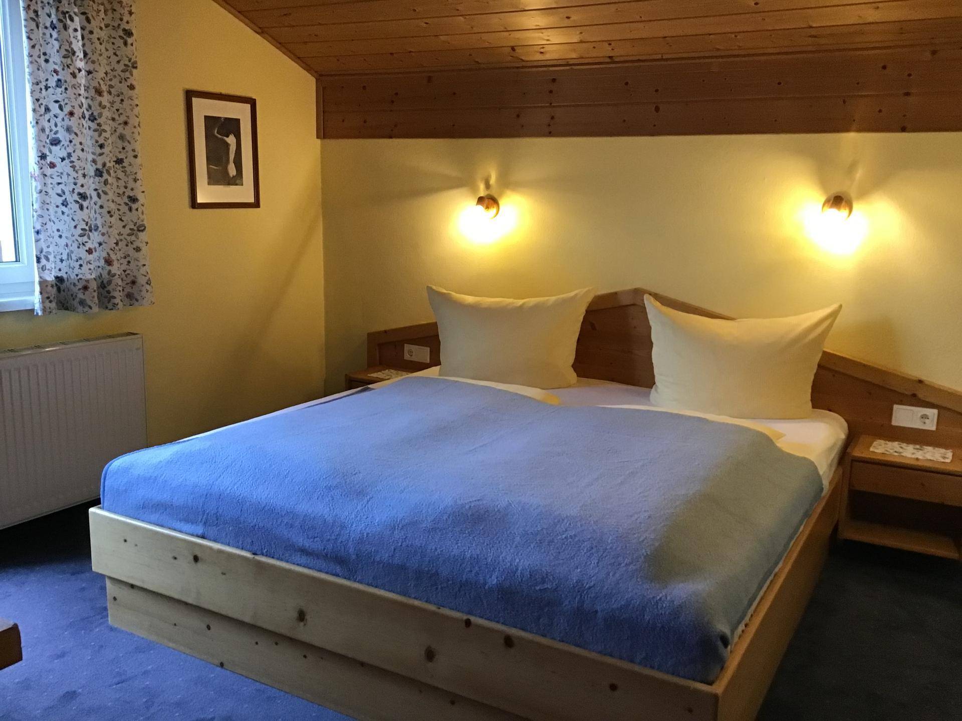 Gemütliches Schlafzimmer mit Doppelbett, Holzdecke und traditioneller Einrichtung.