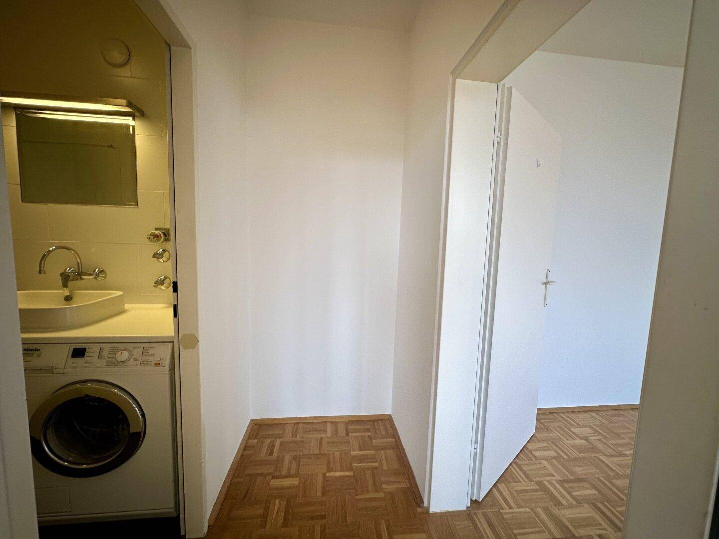 Übergangsbereich mit Parkettboden und Zugang zum Badezimmer, hell und offen gestaltet.