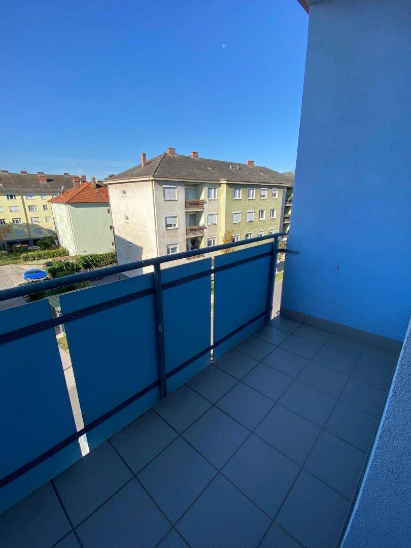 Blauer Balkon mit Fliesenboden und Blick auf die umliegenden Gebäude.