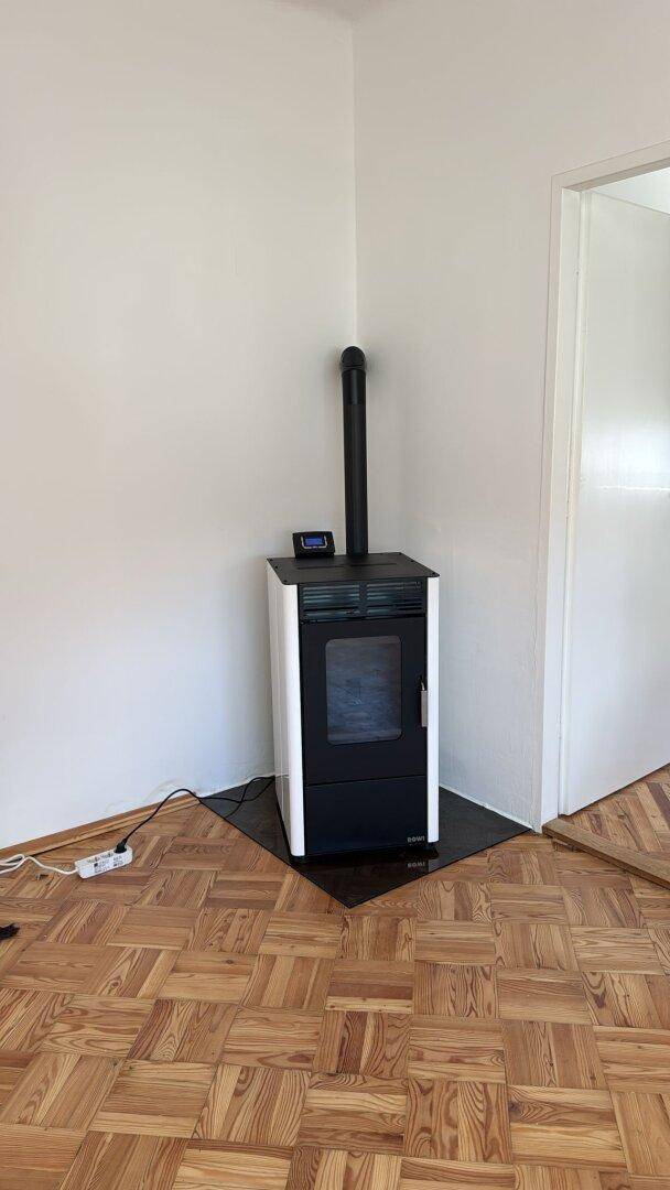 Moderner Holzofen in einem hellen Raum mit klassischem Parkettboden.