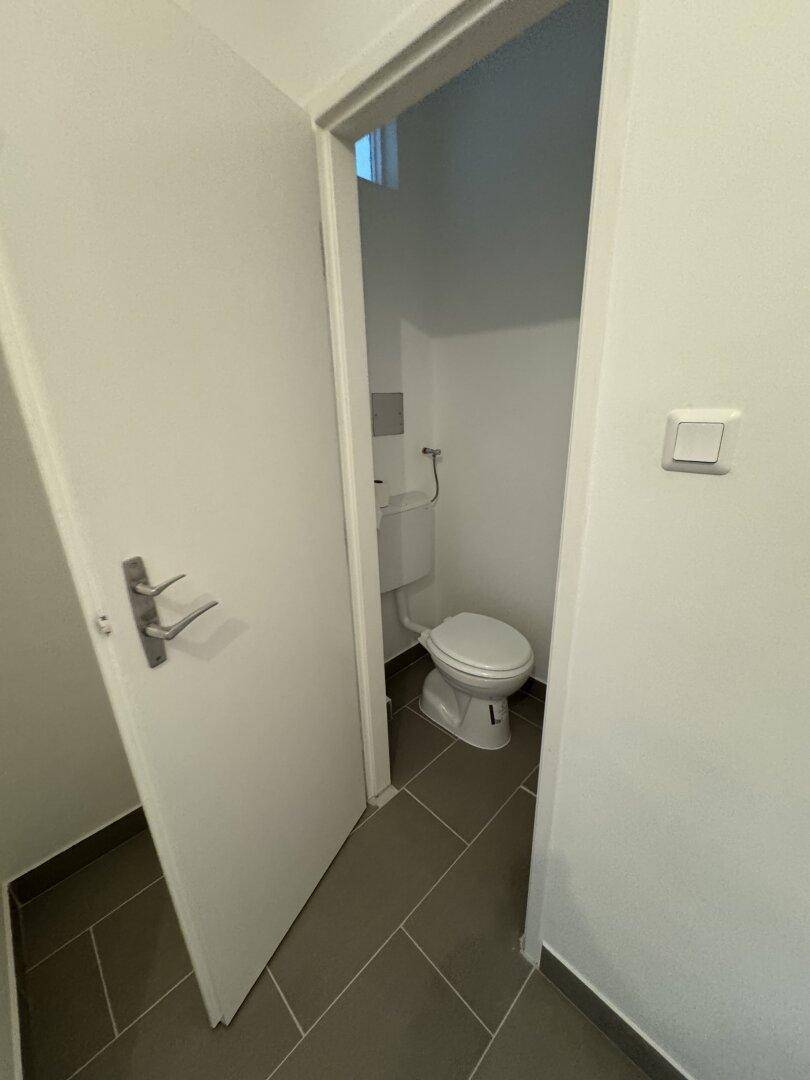 Kleines separates WC mit Toilette und Fliesenboden.