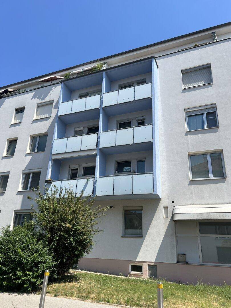 Fassade eines Wohnhauses mit mehreren blauen Balkonen und großen Fenstern.