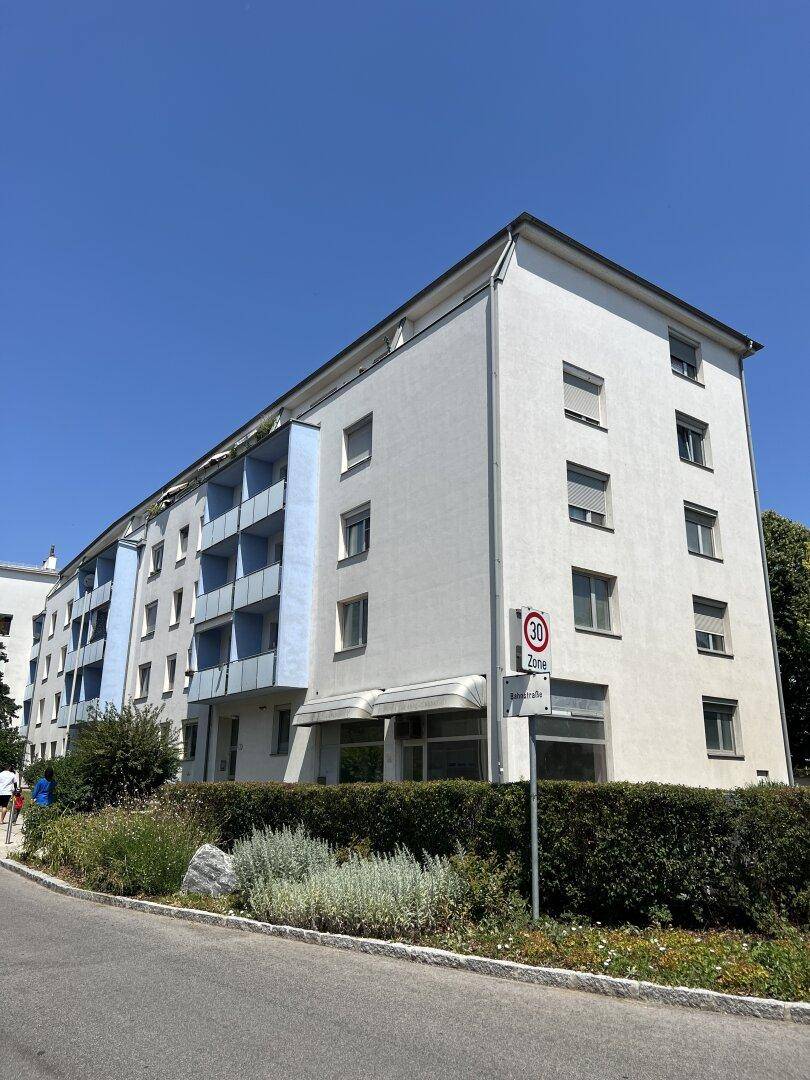 Modernes Wohngebäude mit blauen Balkonen und gepflegter Außenanlage.