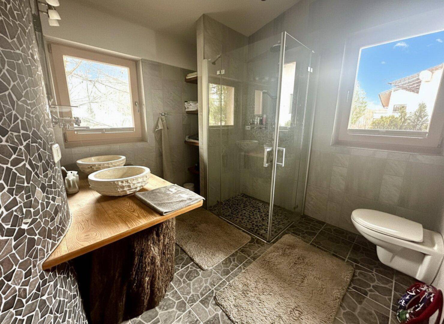 Modernes Badezimmer mit begehbarer Dusche, Doppelwaschbecken und Natursteinfliesen.
