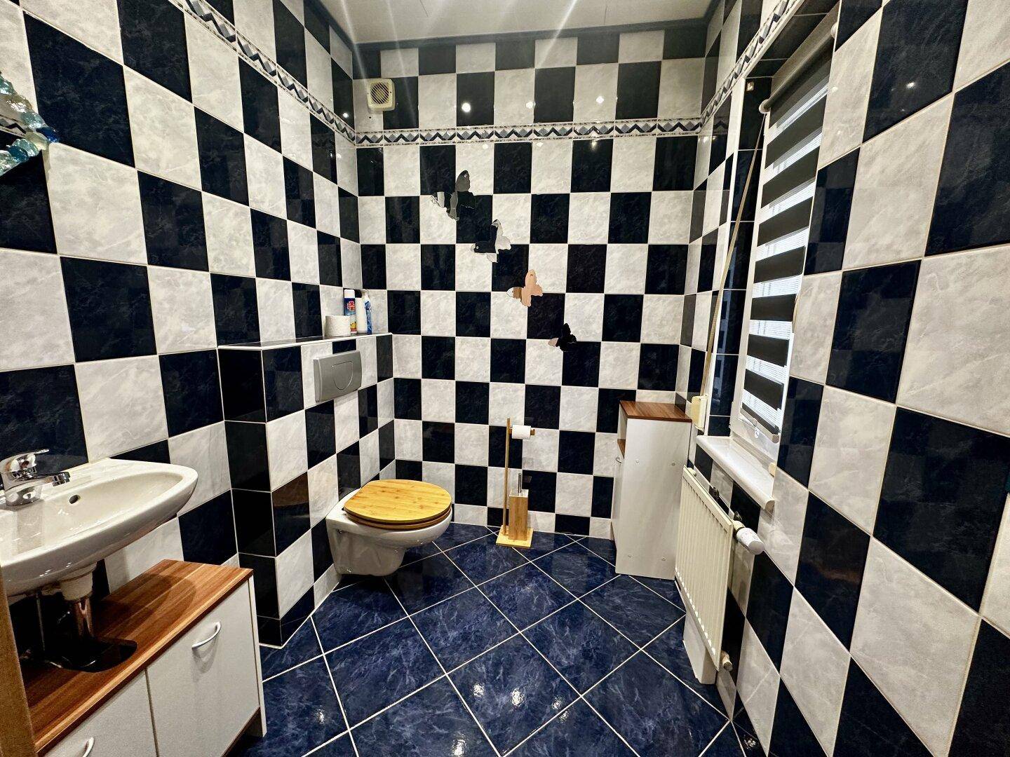 Kleines Badezimmer mit auffälligen schwarz-weißen Fliesen und Fenster.