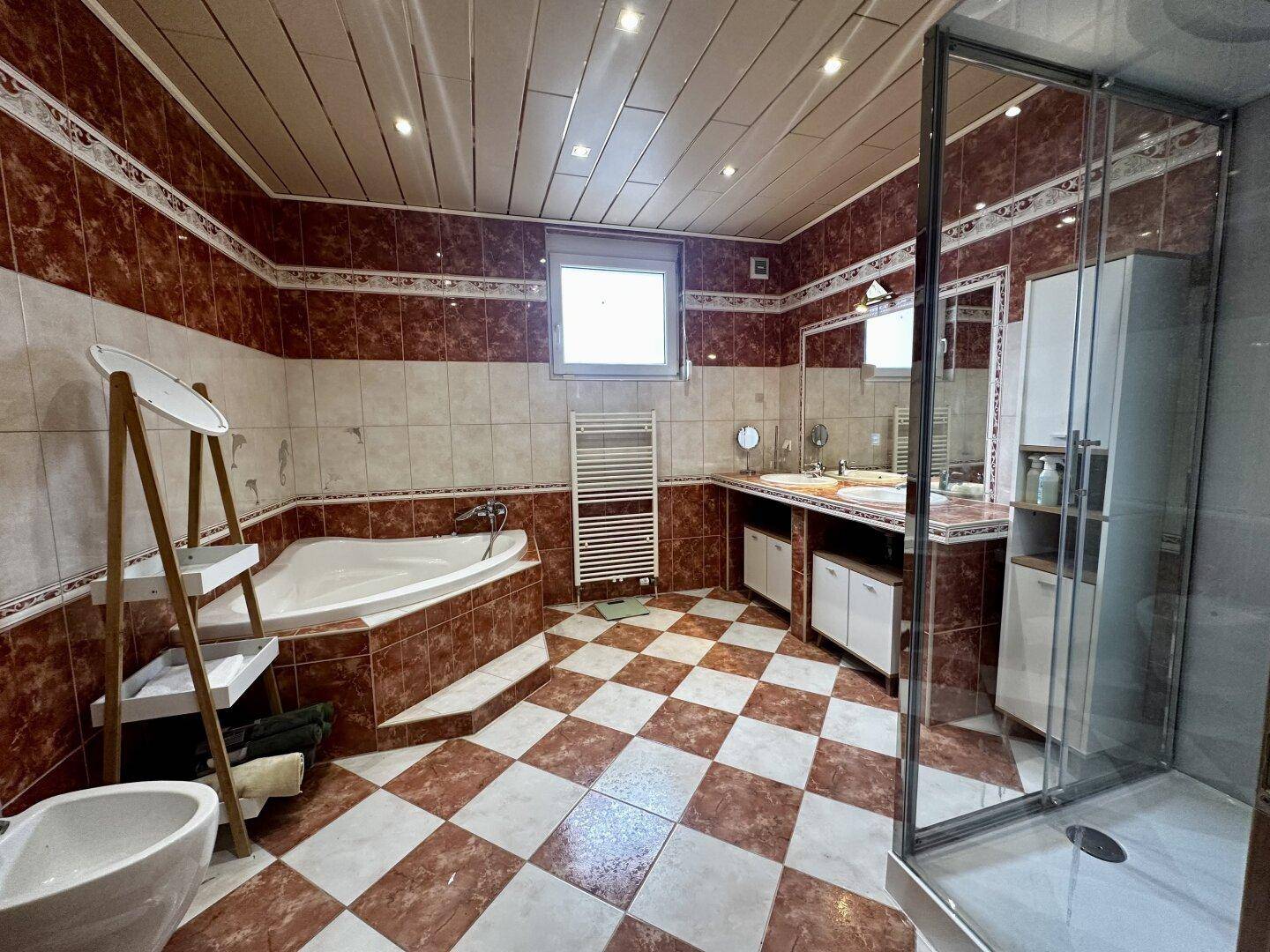 Geräumiges Badezimmer mit Badewanne, Dusche, Doppelwaschbecken und Fenster.