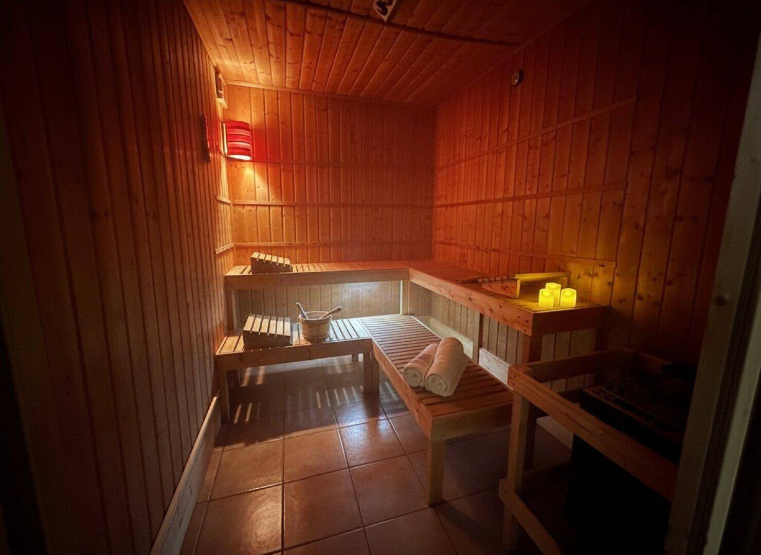 Gemütliche Holzsauna mit Bänken und stimmungsvoller Beleuchtung für Entspannung.
