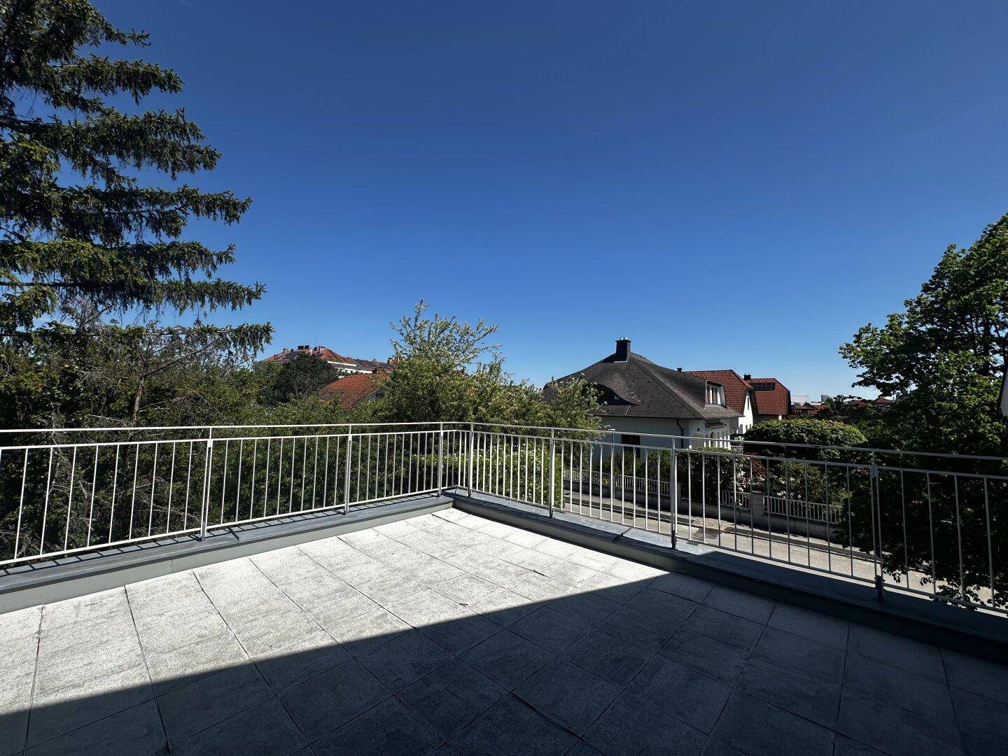Dachterrasse mit Fliesenboden und Blick über die Dächer der umliegenden Häuser.