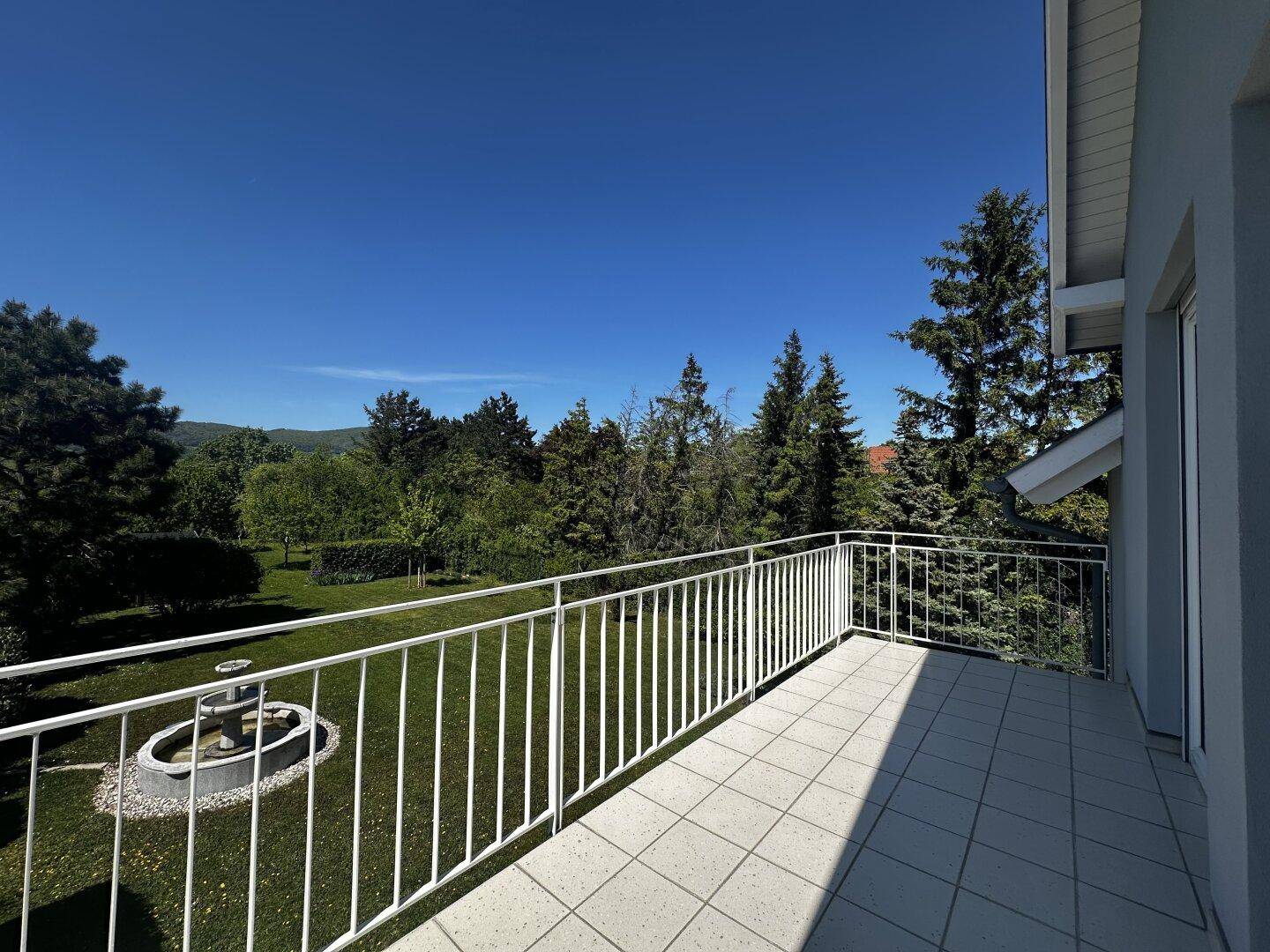 Geräumiger Balkon mit Fliesenboden und weitem Blick über den Garten und die Landschaft.