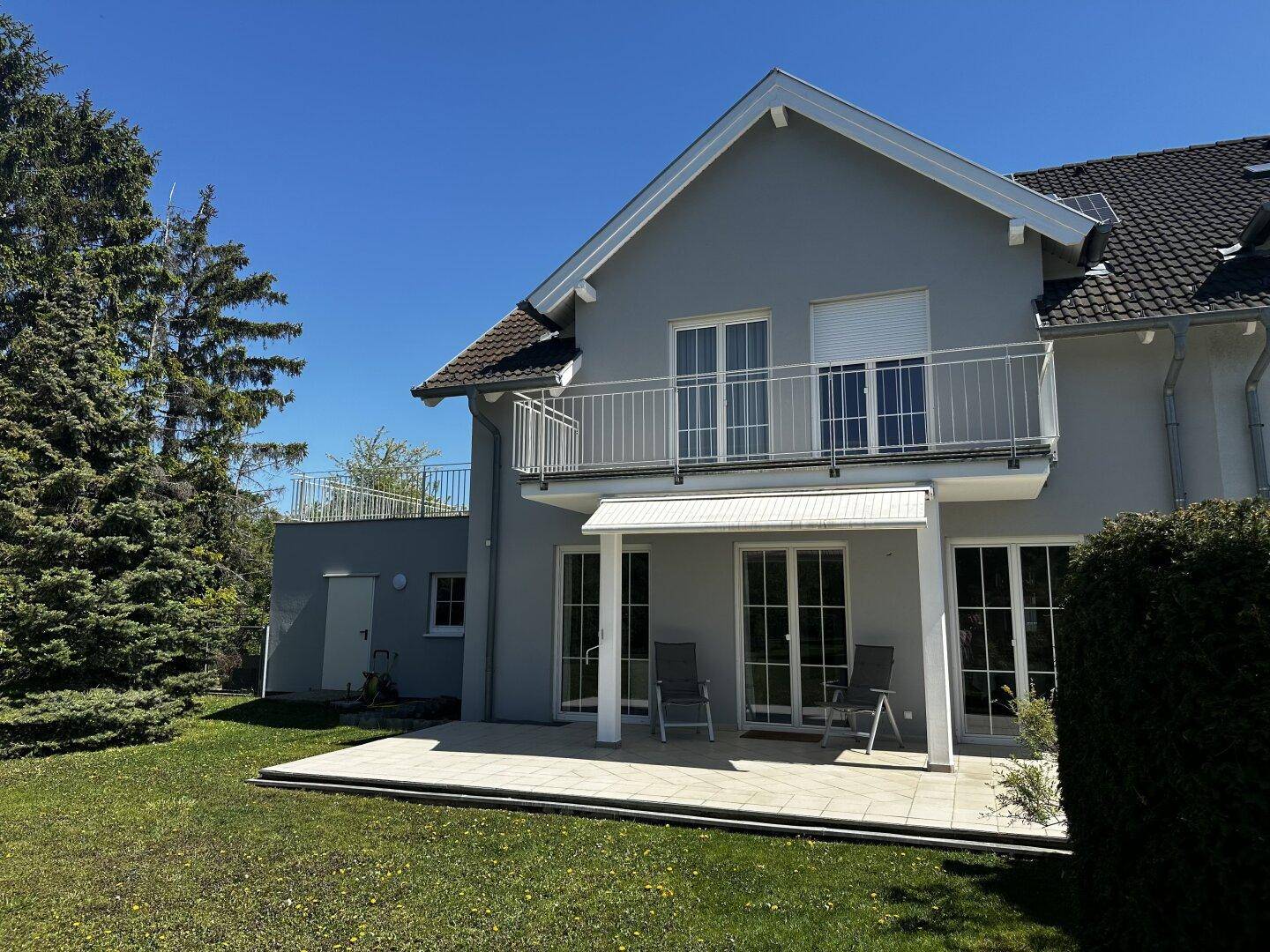 Sonniger Terrassenbereich mit Gartenmöbeln und Zugang zum großen Garten.