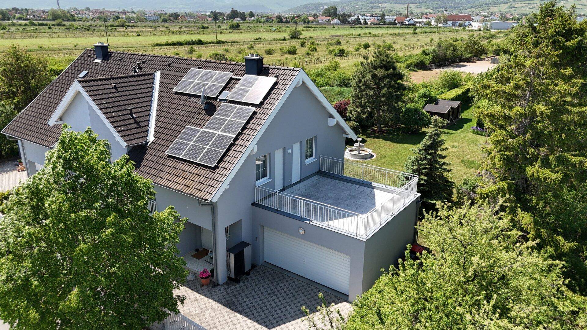 Modernes Einfamilienhaus mit Photovoltaikanlage auf dem Dach und großer Terrasse über der Garage.