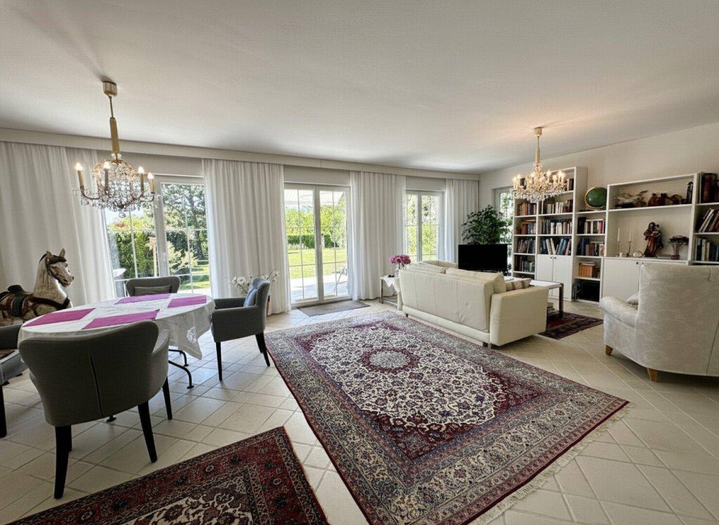 Helles Wohn- und Esszimmer mit Fliesenboden, großen Fenstern und Zugang zum Garten.