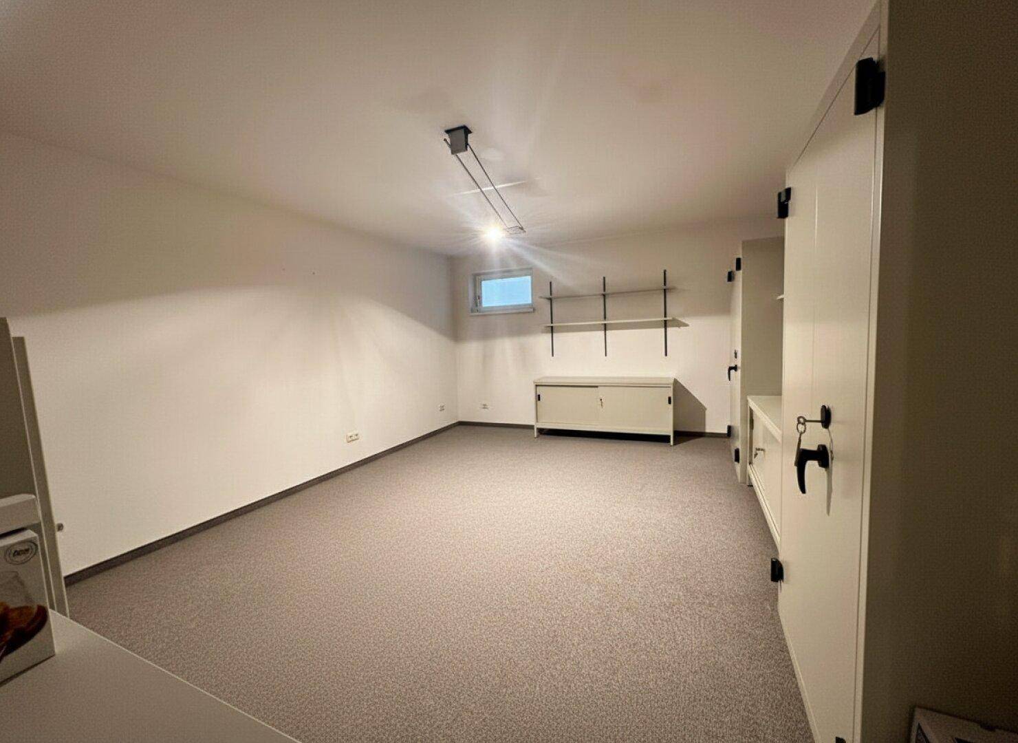 Geräumiger Abstellraum mit Teppichboden, Regalen und Schränken, ideal für Lagerzwecke.