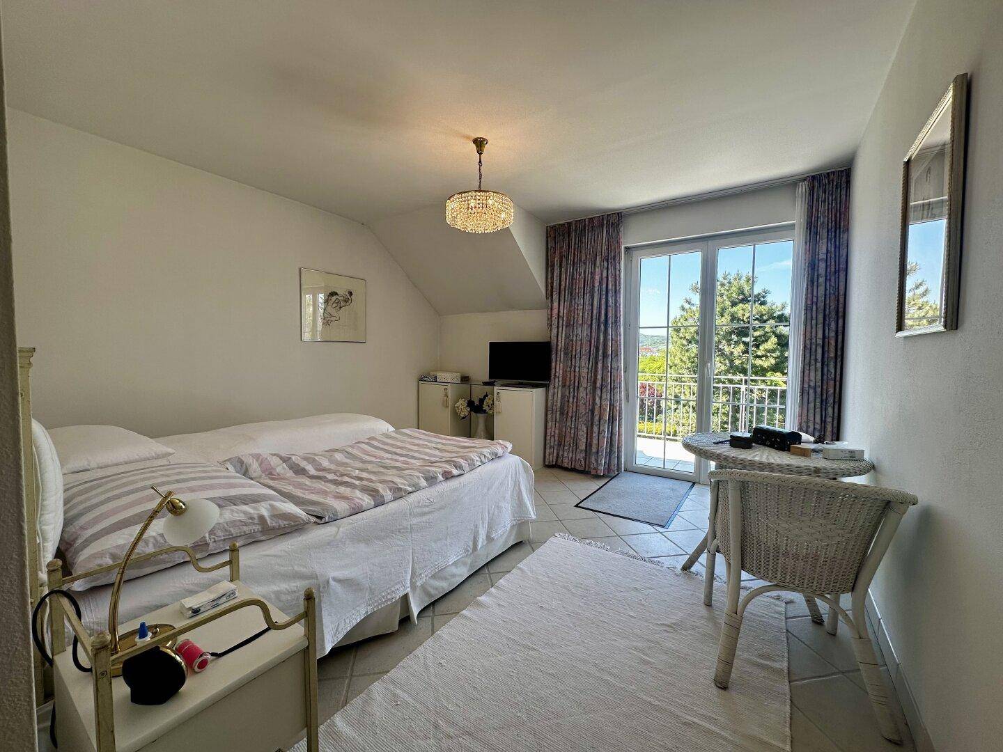 Gemütliches Schlafzimmer mit zwei Betten, Fliesenboden und Balkonzugang mit schöner Aussicht.
