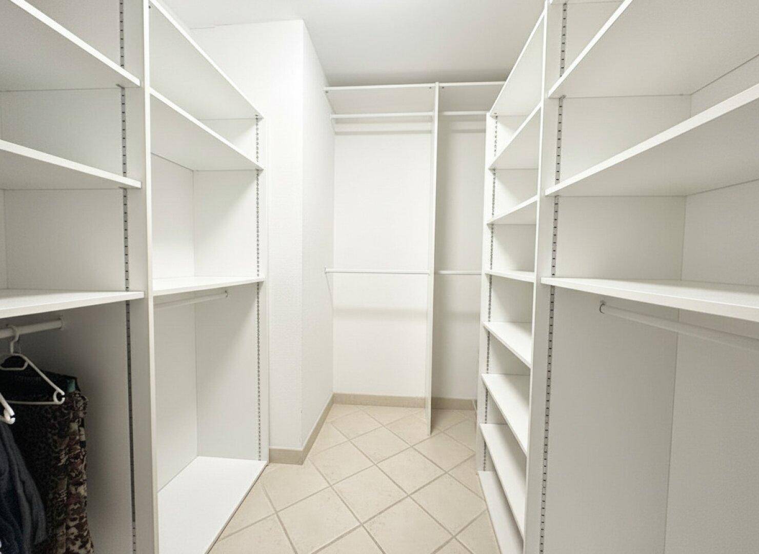 Geräumiger begehbarer Kleiderschrank mit vielen Regalen und Aufhängemöglichkeiten.