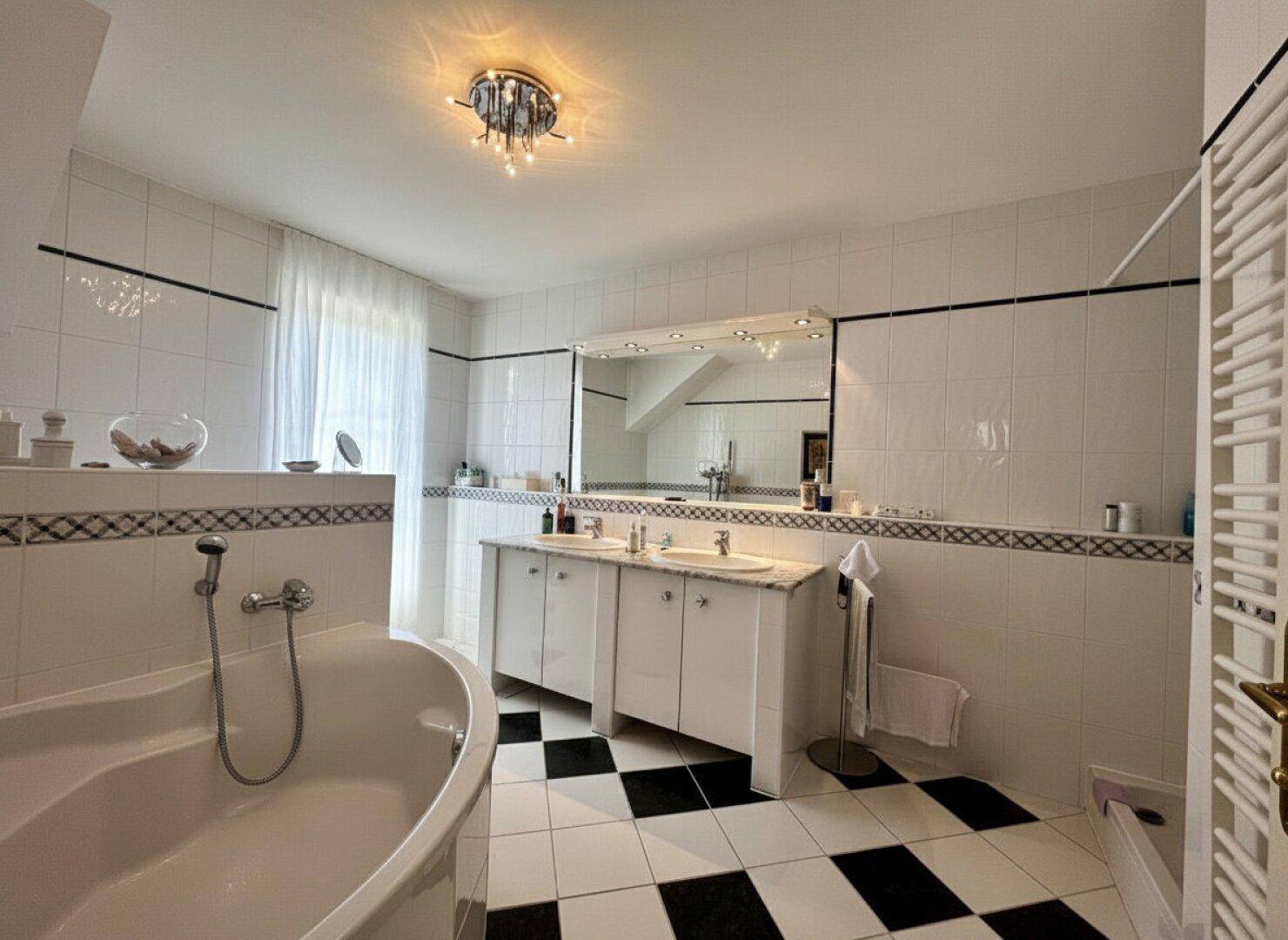 Großes Badezimmer mit Badewanne, Doppelwaschbecken und Schachbrettmuster-Fliesen.