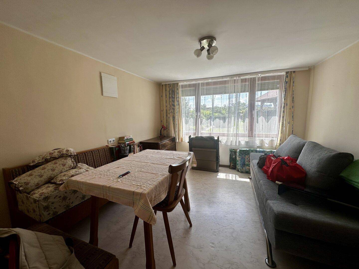 Gemütlicher Wohn- und Essbereich mit Sofa, Esstisch und großem Fenster.