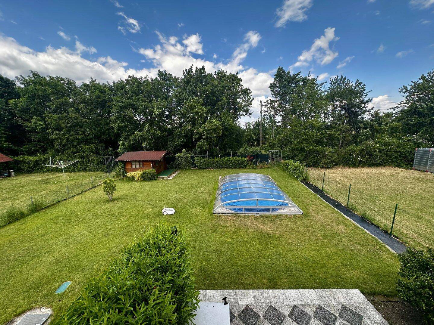 Großer, gepflegter Garten mit Rasenfläche, Pool mit Überdachung und Gartenhaus.