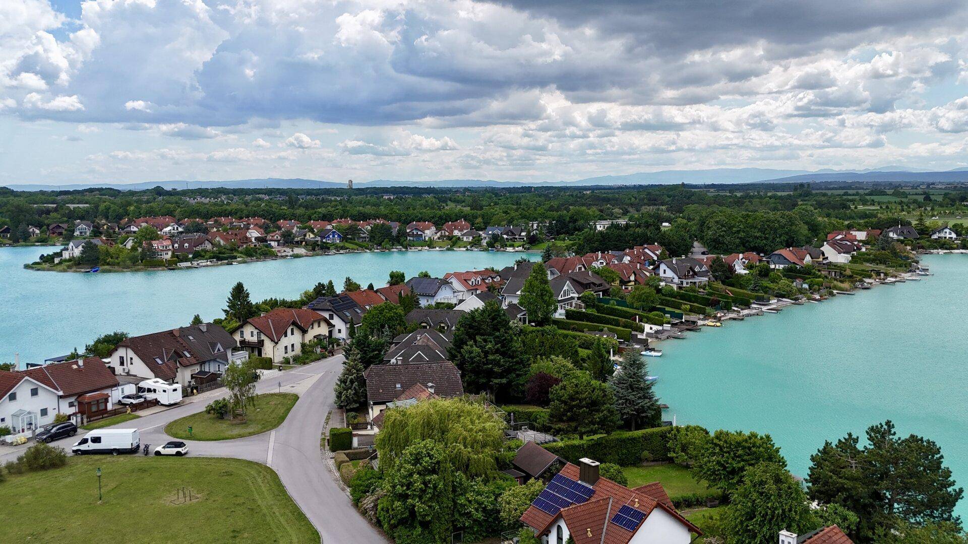 Panoramablick auf die Wohnsiedlung am Seeufer mit vielen Häusern und grüner Landschaft.