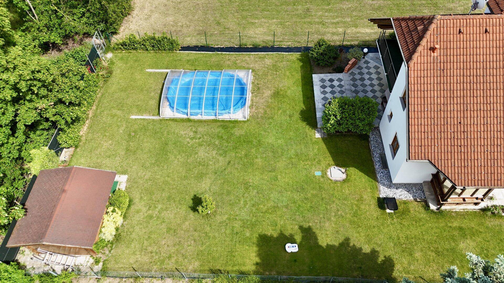 Draufsicht auf das Haus mit Garten, Pool, Gartenhaus und gepflasterter Terrasse.