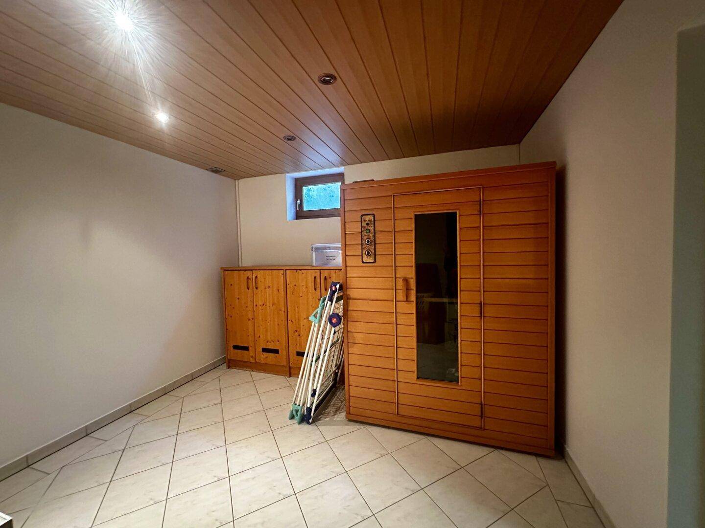 Kellerraum mit integrierter Sauna, Fliesenboden und kleinem Fenster.
