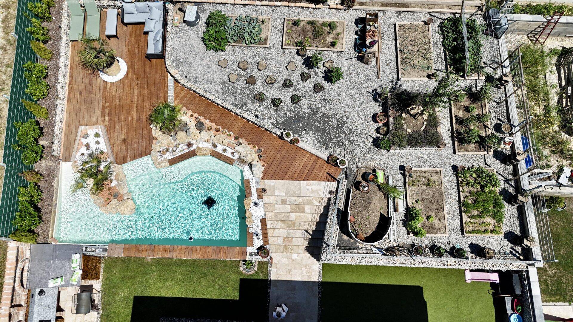 Luftaufnahme des Gartens mit Pool, Holzdeck und verschiedenen Pflanzbereichen.