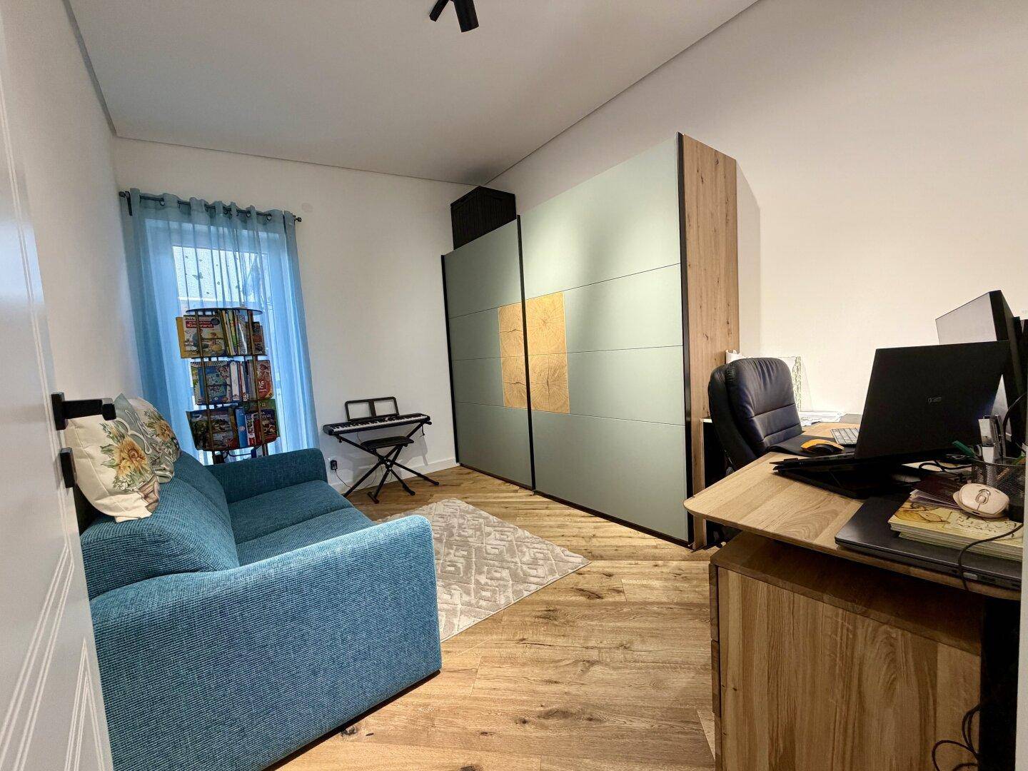 Arbeitszimmer mit Sofa, Schreibtisch und Schrank, ideal als Home-Office oder Gästezimmer.