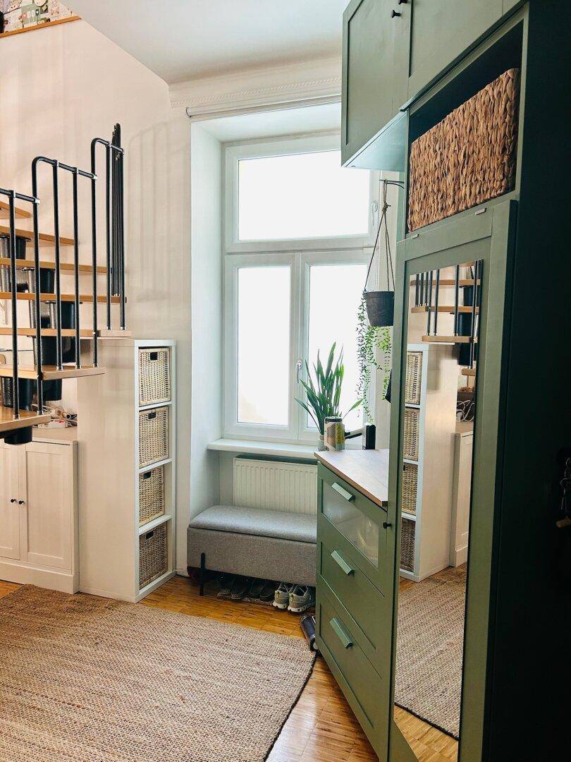 Heller Flur mit praktischen Schränken, Spiegel und einer eleganten Wendeltreppe, die nach oben führt.
