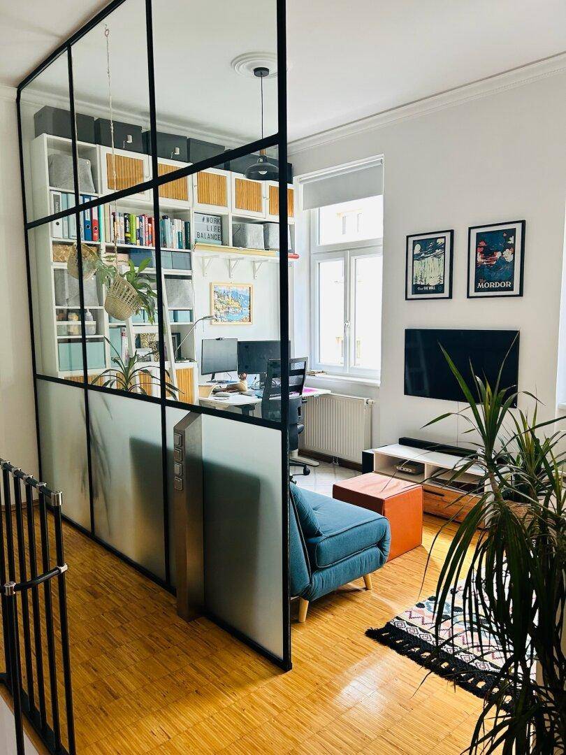 Moderner Arbeitsbereich mit Glaswand, Schreibtisch und Blick auf den Flur, hell und offen gestaltet.