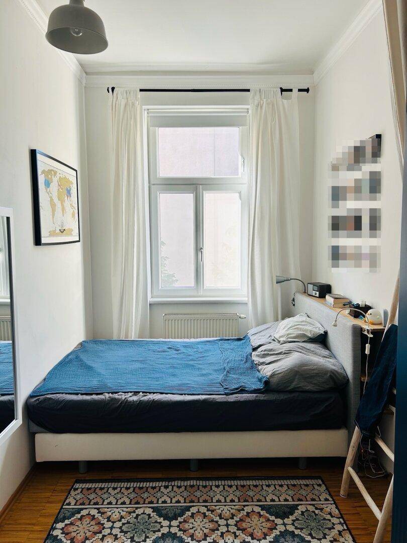 Gemütliches Schlafzimmer mit Doppelbett, Teppich und großem Fenster, das viel Licht spendet.