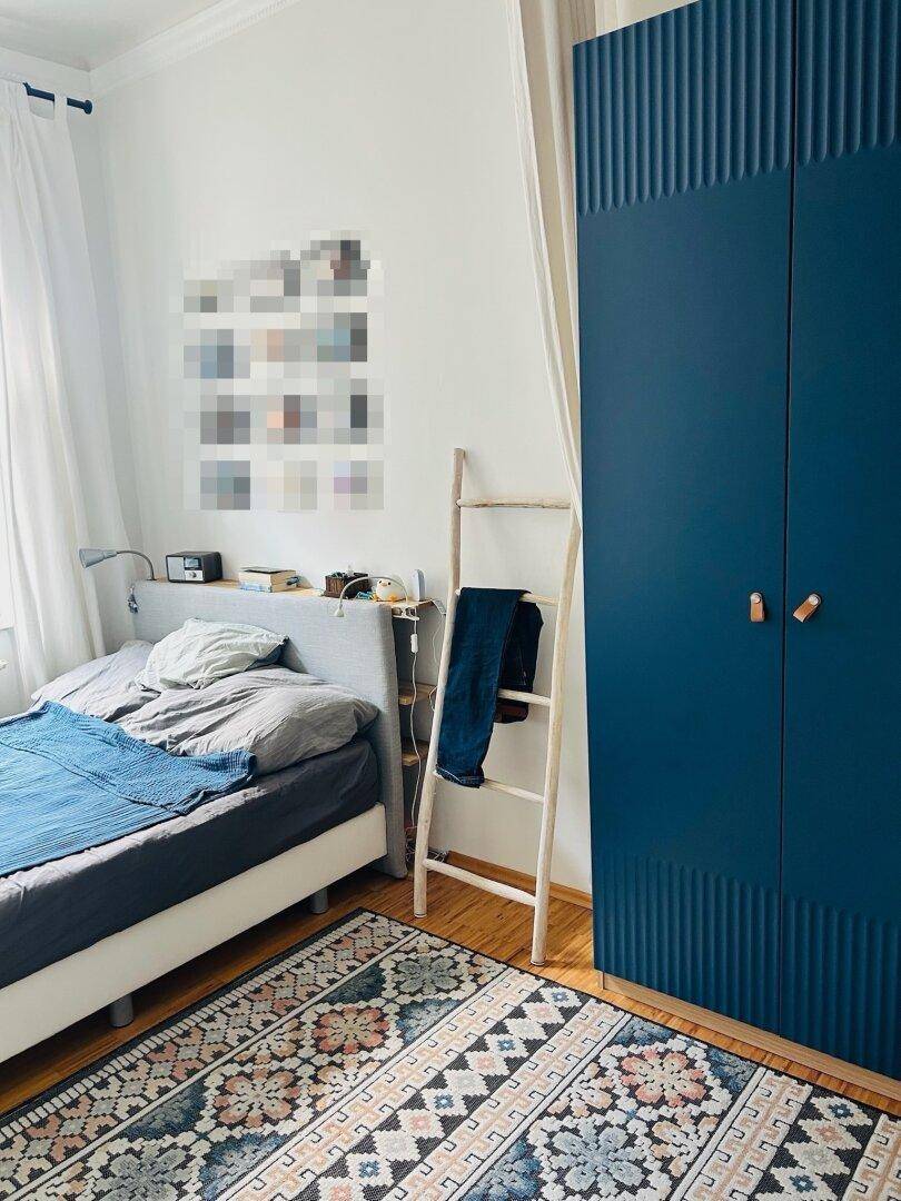 Schlafzimmer mit Doppelbett, Teppich und einem modernen blauen Kleiderschrank, der viel Stauraum bietet.