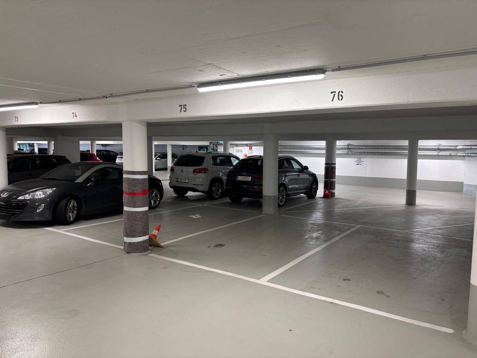 Geräumige Tiefgarage mit mehreren geparkten Fahrzeugen und klar markierten Stellplätzen.