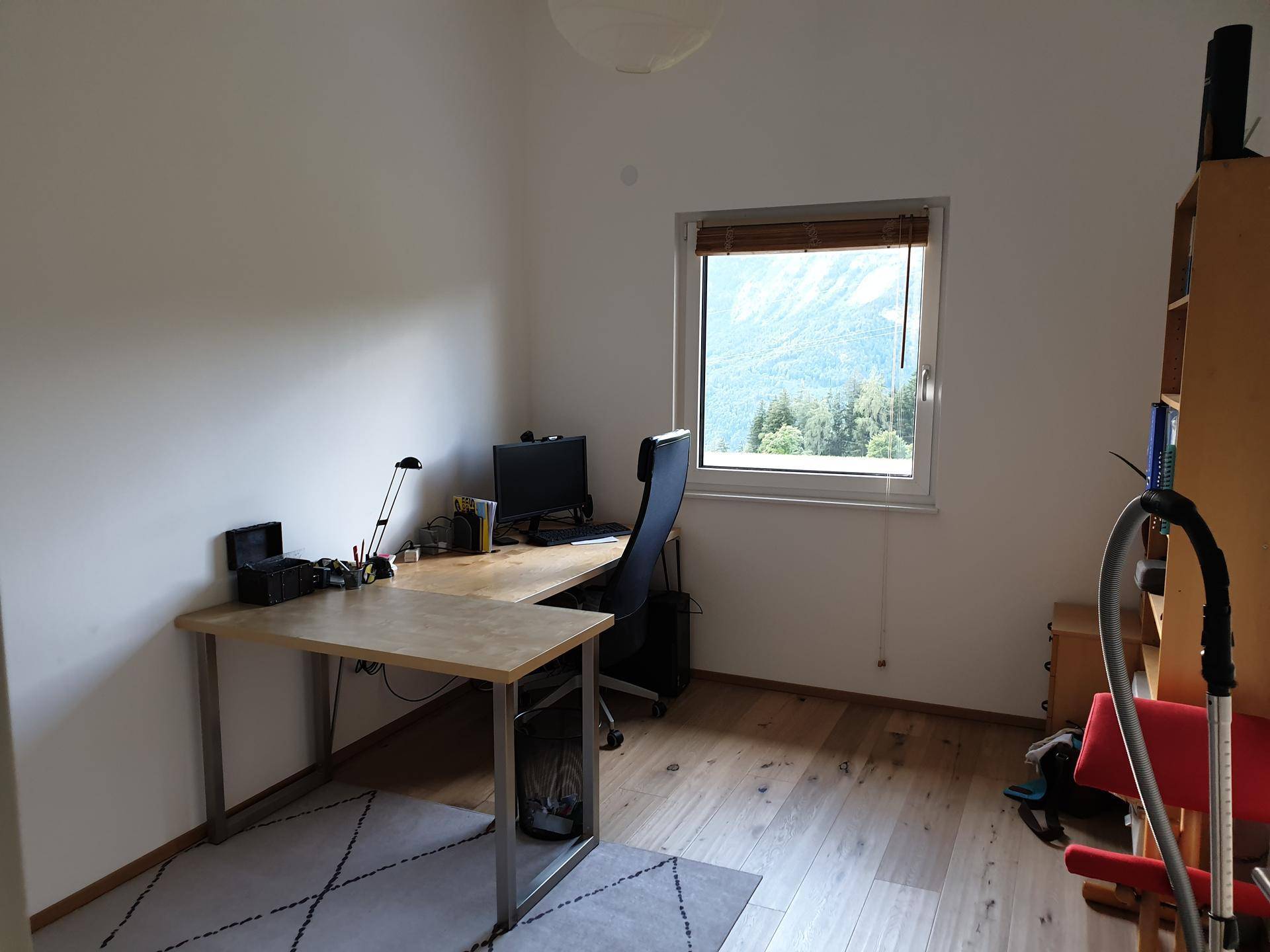 Ruhiges Arbeitszimmer mit Holzschreibtisch und Fenster mit Blick auf die umliegende Berglandschaft.