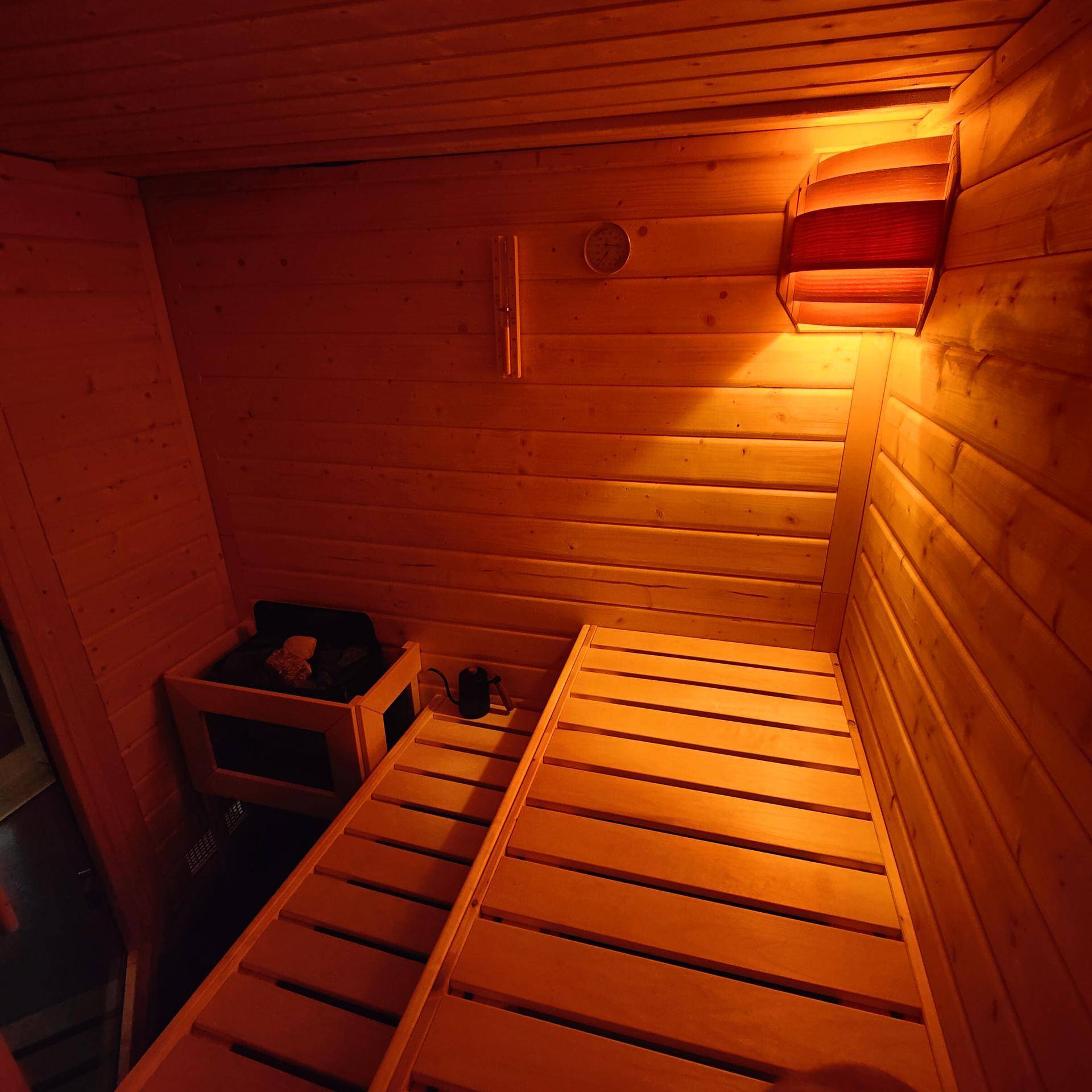 Gemütliche Holzsauna mit Bänken und warmer Beleuchtung für entspannende Momente.