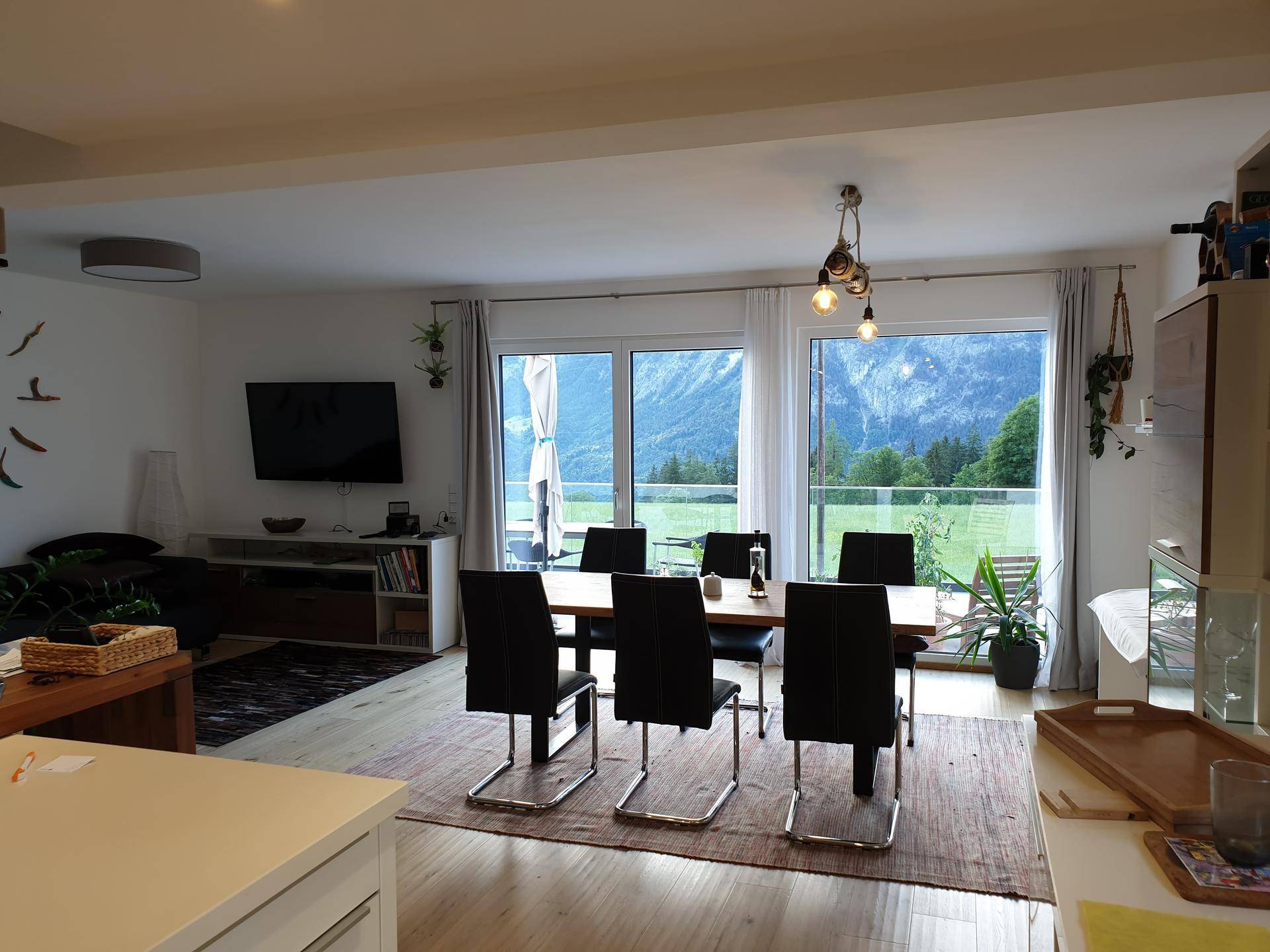 Offener Wohn- und Essbereich mit großem Esstisch und Panoramafenstern mit beeindruckendem Bergblick.