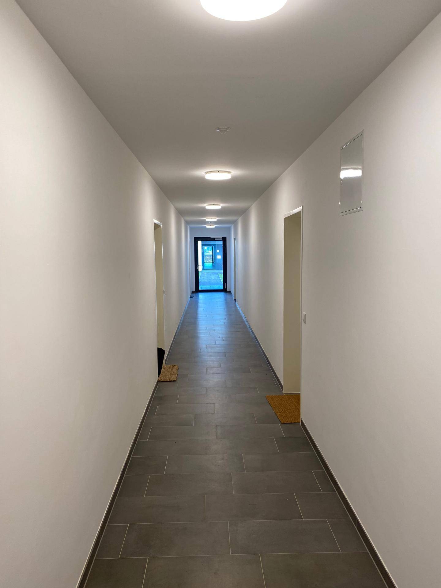Langer, heller Flur mit Fliesenboden und mehreren Türen zu den Zimmern.
