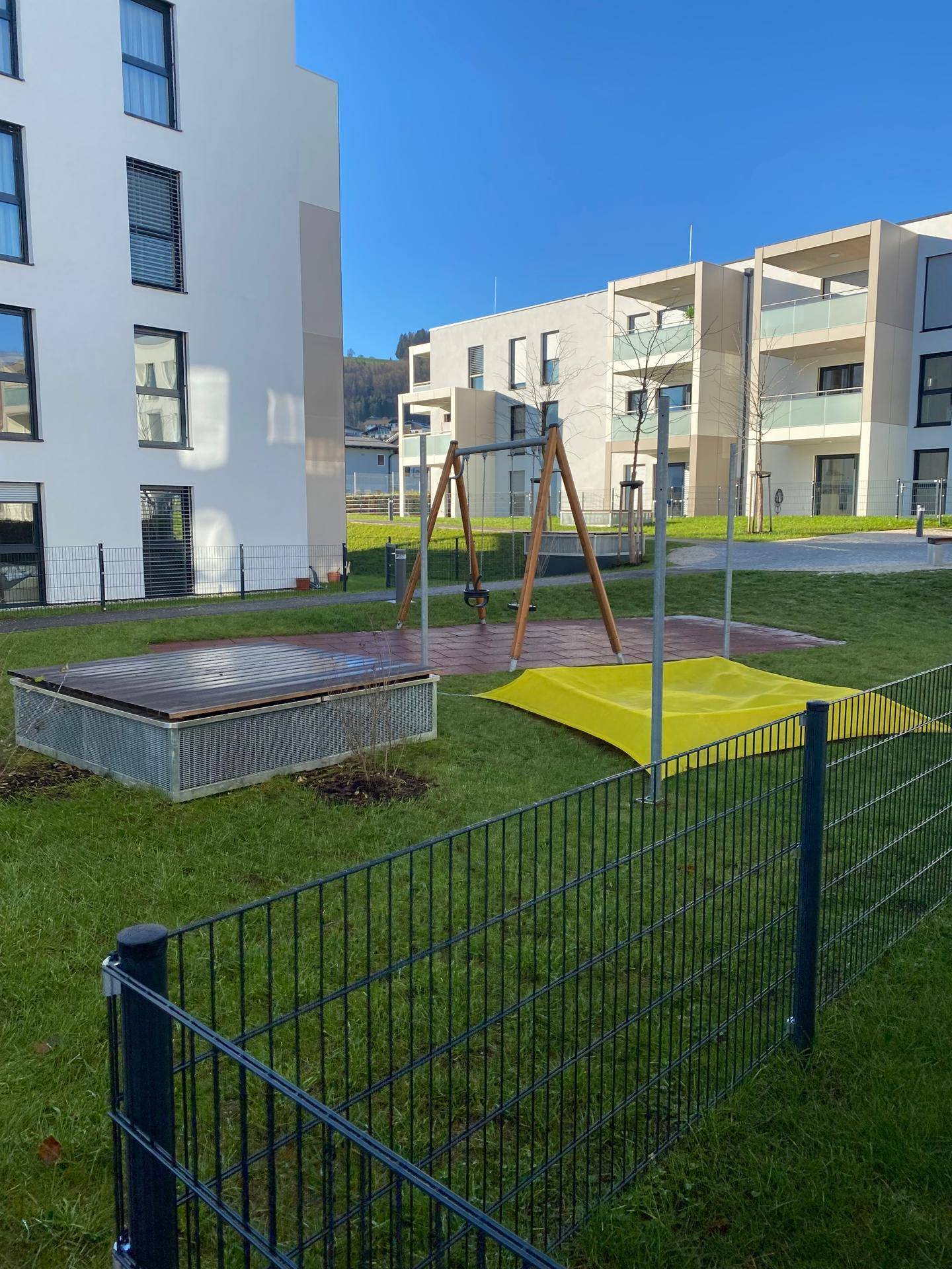 Kinderspielplatz mit Schaukel und Sandkasten in der Wohnanlage.