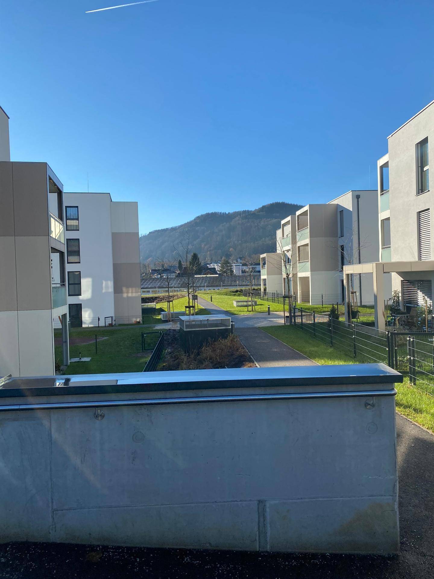 Moderne Wohnanlage mit Grünflächen und Blick auf die umliegenden Berge.