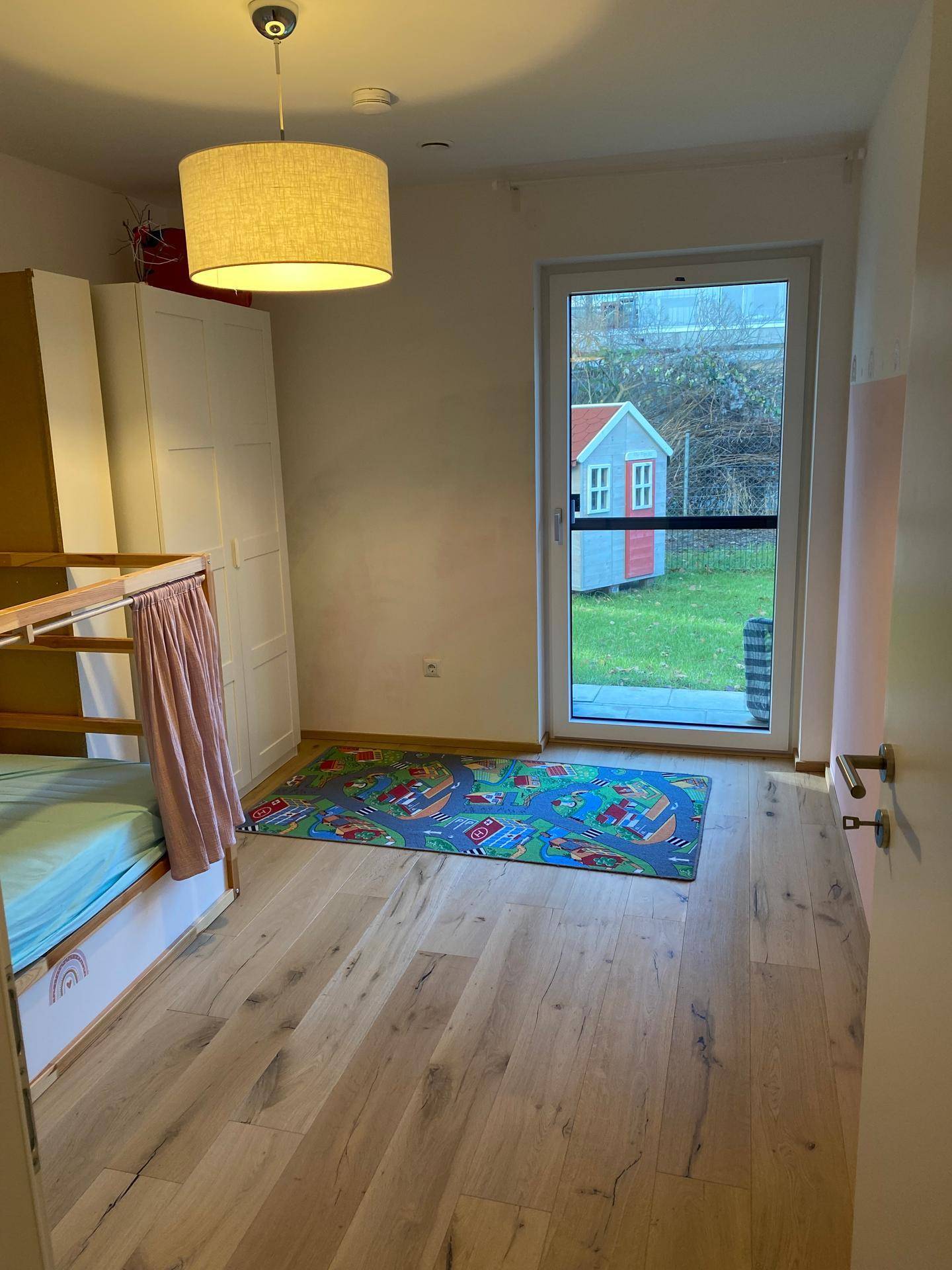 Helles Kinderzimmer mit Holzboden und direktem Zugang zum Außenbereich.