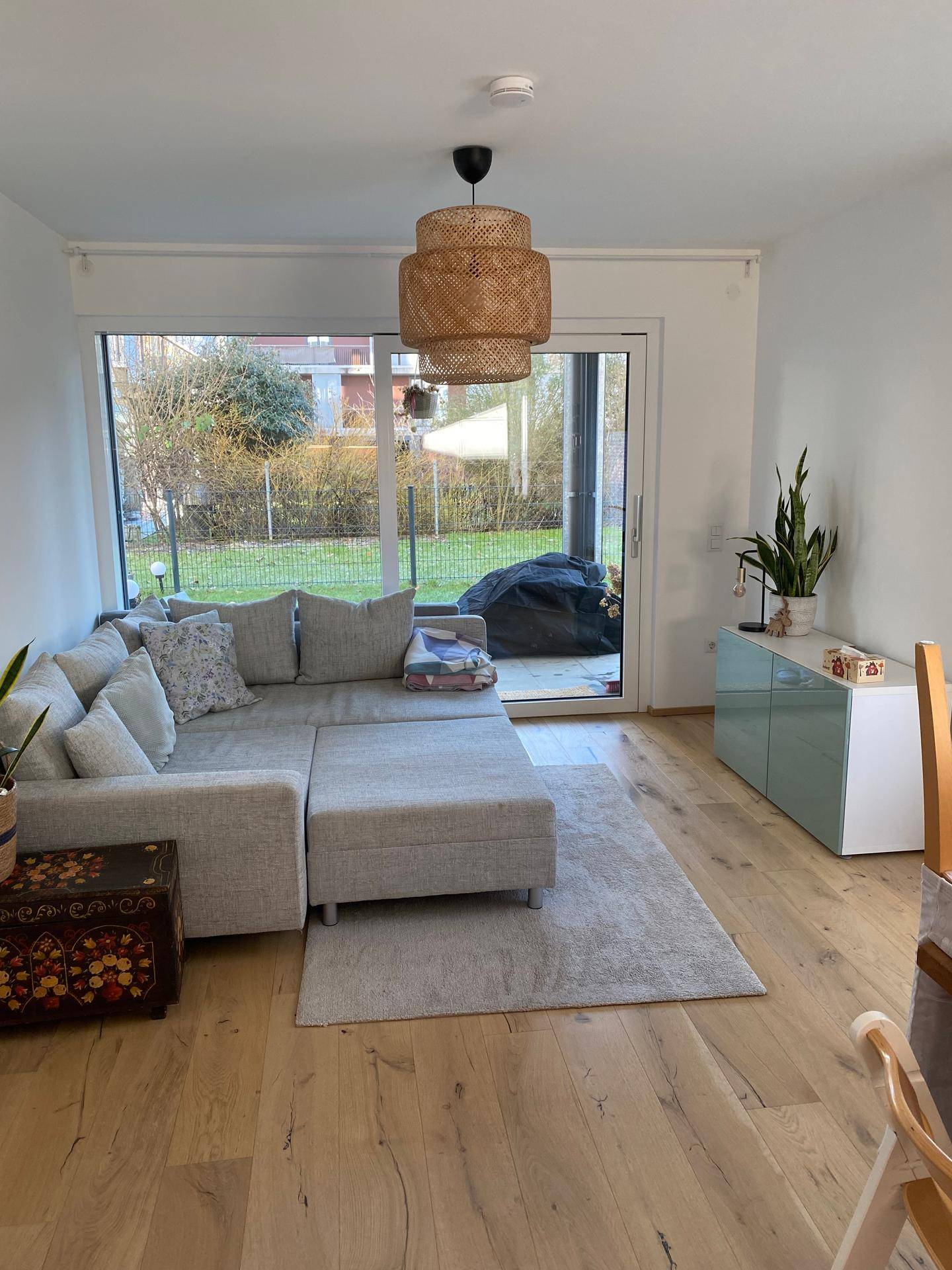Gemütliches Wohnzimmer mit Sofa, Holzboden und großen Fenstern zum Garten.